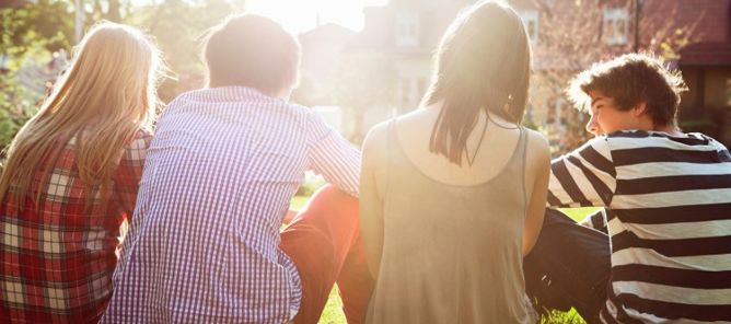 Gjeng med ungdom sitter i solen.